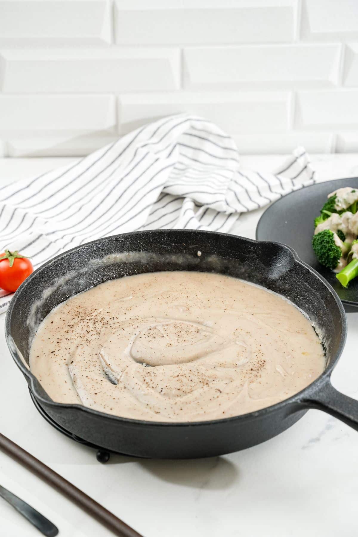 cast iron skillet of vegan bechamel sauce sitting on white table