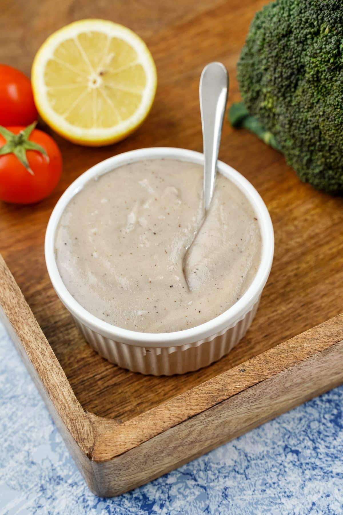 white ramekin of vegan bechamel sauce on wood tray