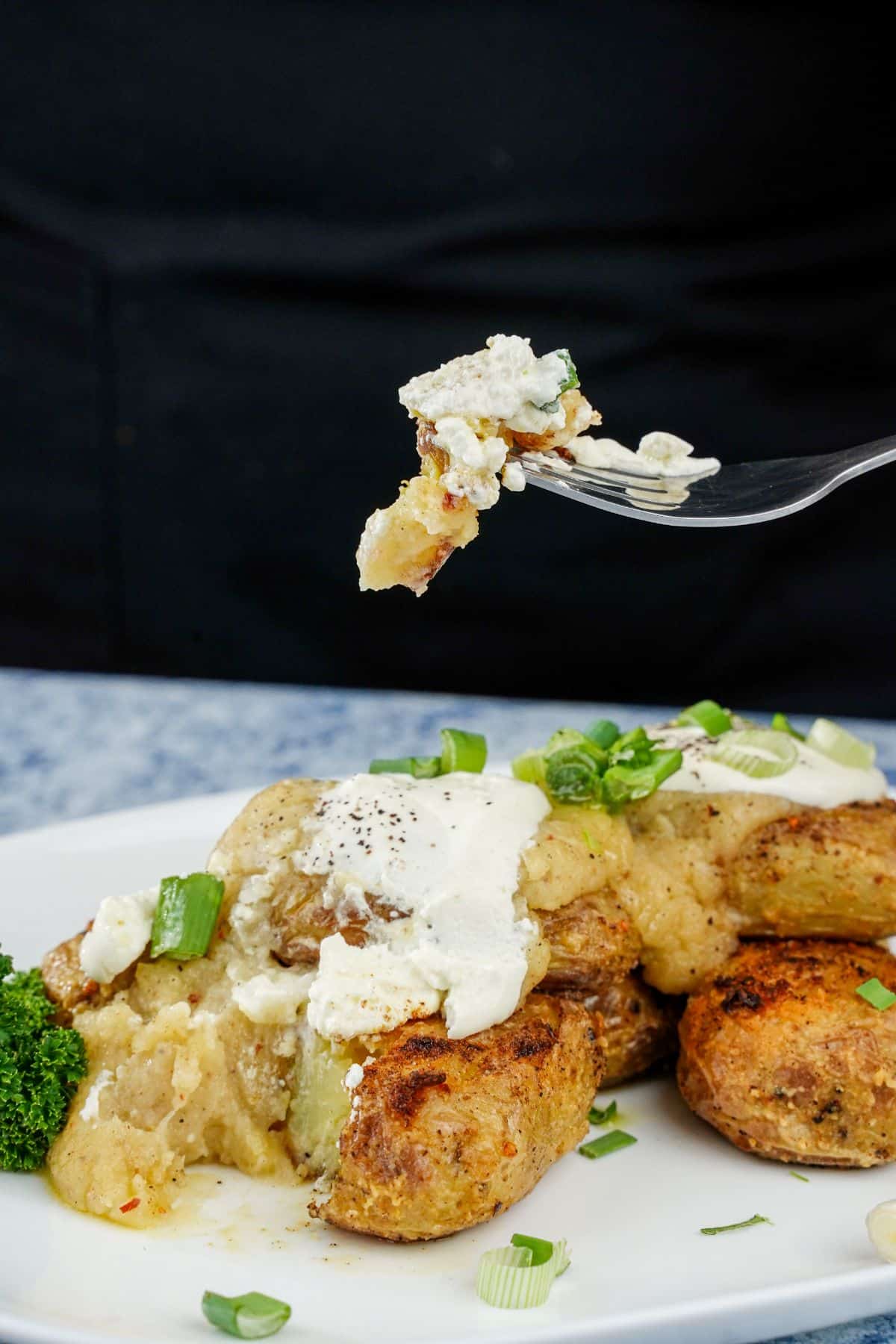 fork of potato and sauce held above white plate of fiesta potatoes