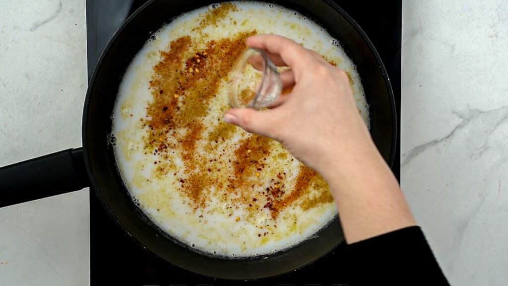 adding spices to skillet of sauce
