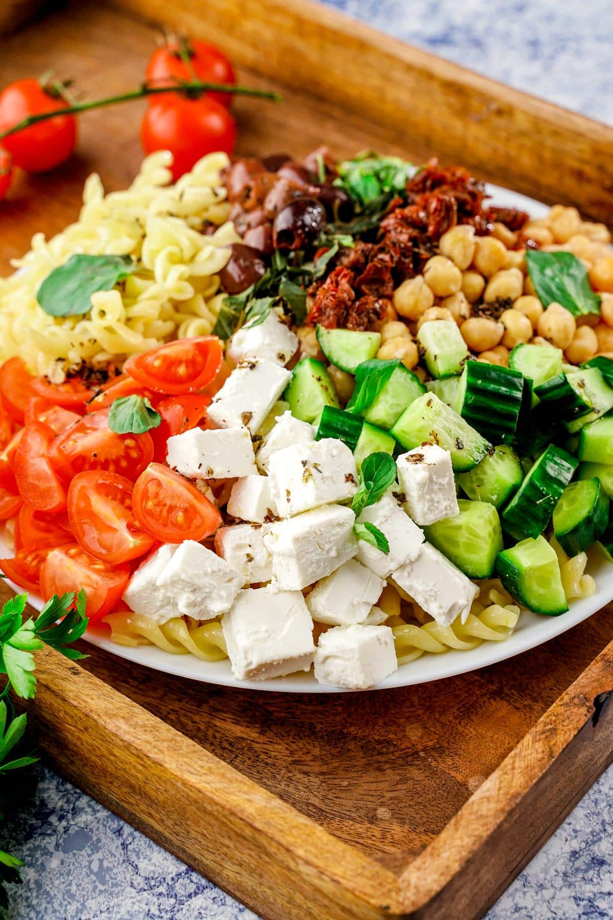 vegan Greek pasta salad in bowl on top of wood tray