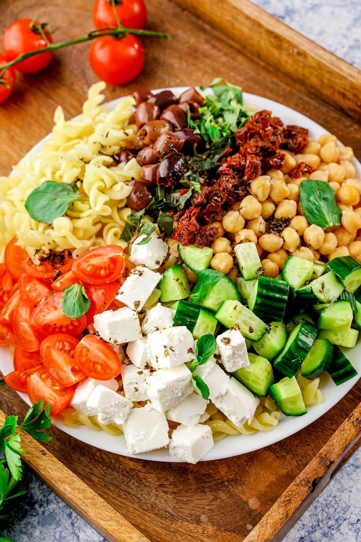 white bowl of vegan Greek pasta salad on wood tray