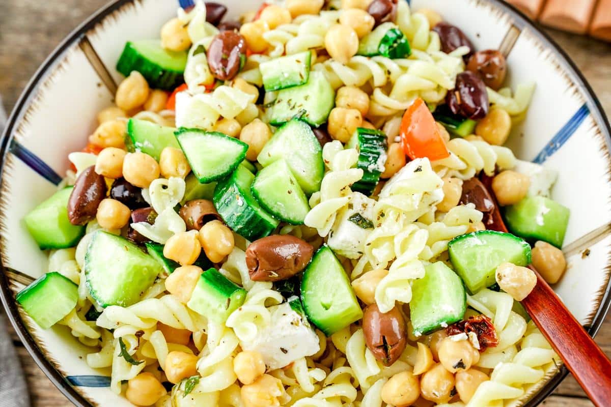 white and blue striped bowl of Greek pasta salad