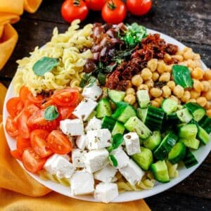 white bowl of vegan Greek pasta salad on wood table