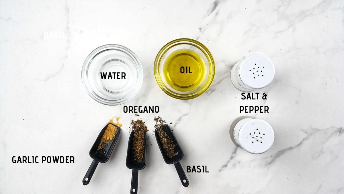 herbs and oils in measuring cups on marble table