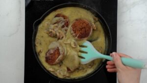 lentil patties being stirred into mushroom gravy with spoon