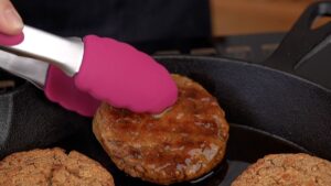 pink tongs moving lentil patties out of skillet