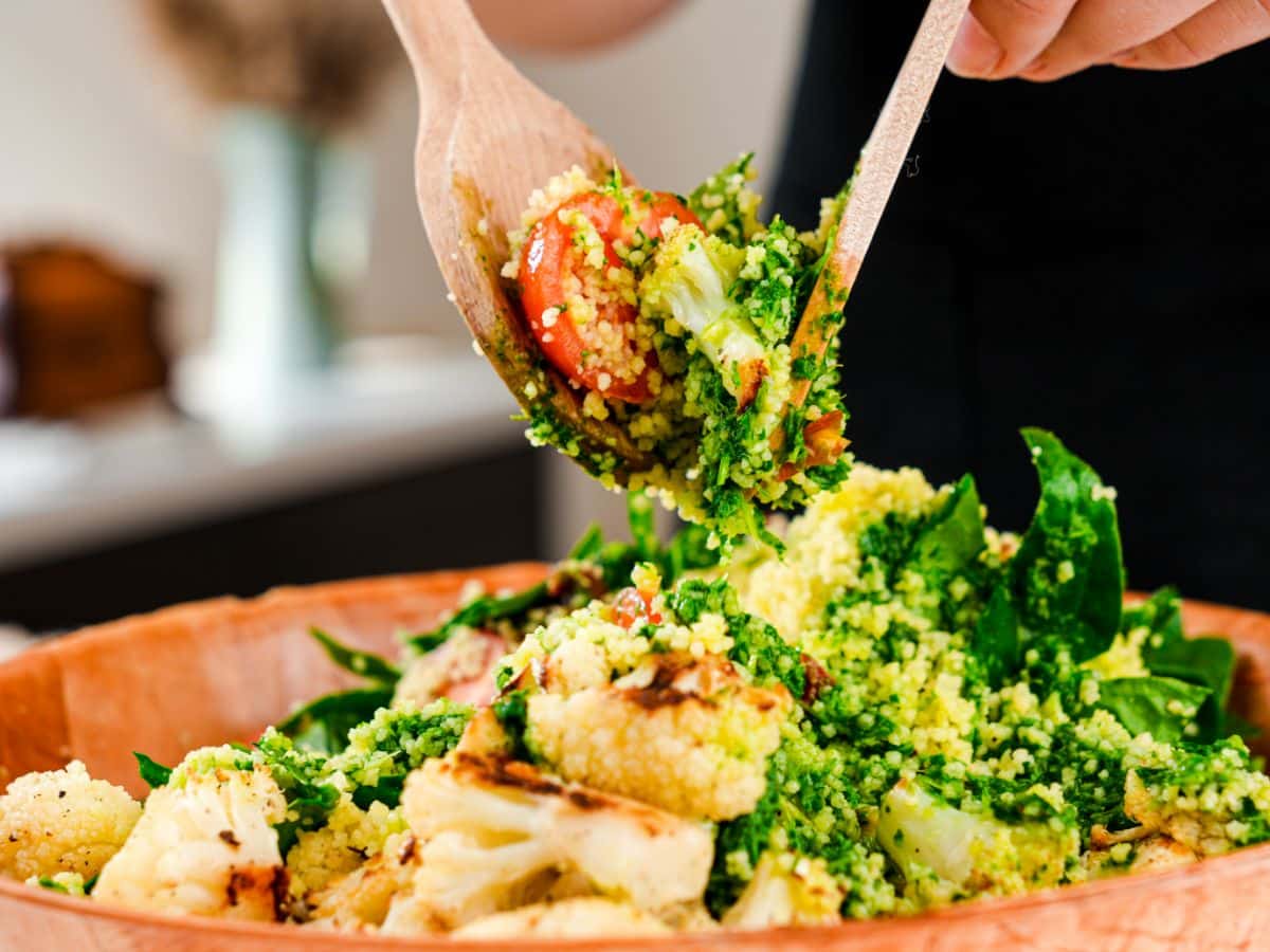 salad spoons holding serving of couscous salad above bowl