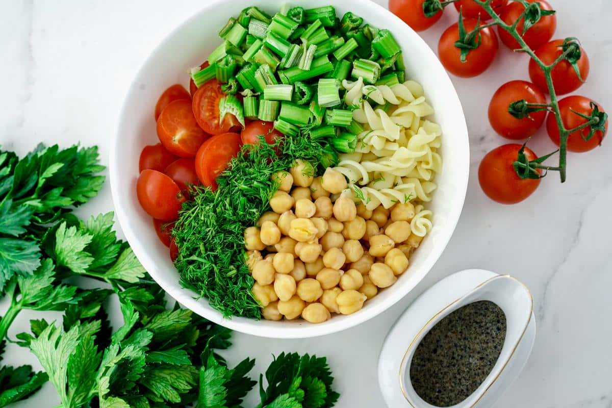 vegan pasta salad ingredients in large white bowl on table