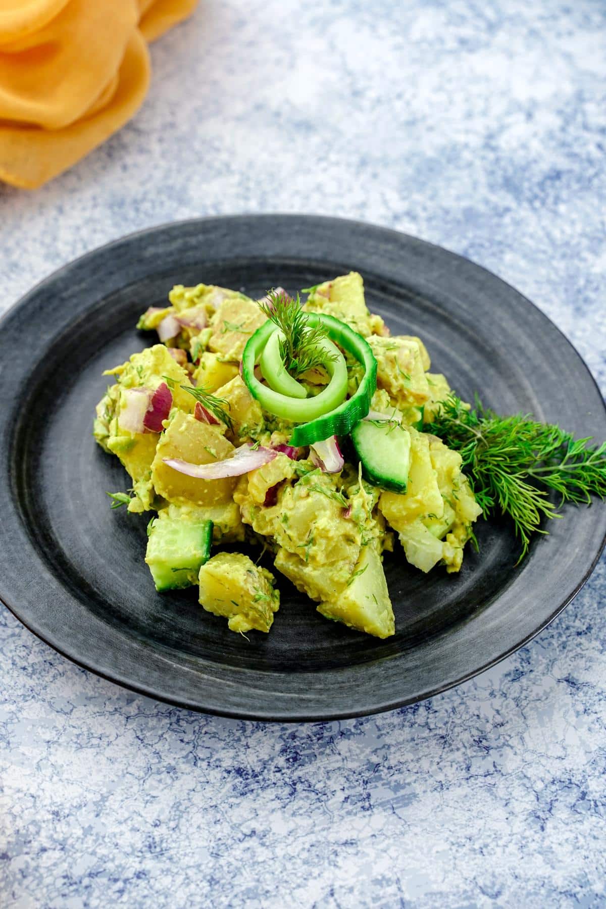gray table under black plate of vegan potato salad