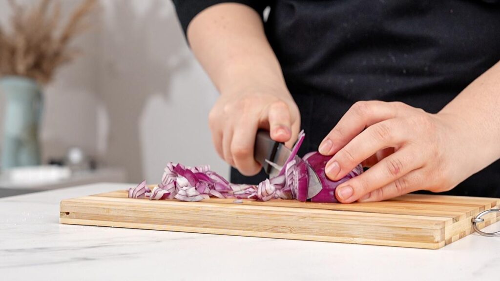 red onion being chopped on board
