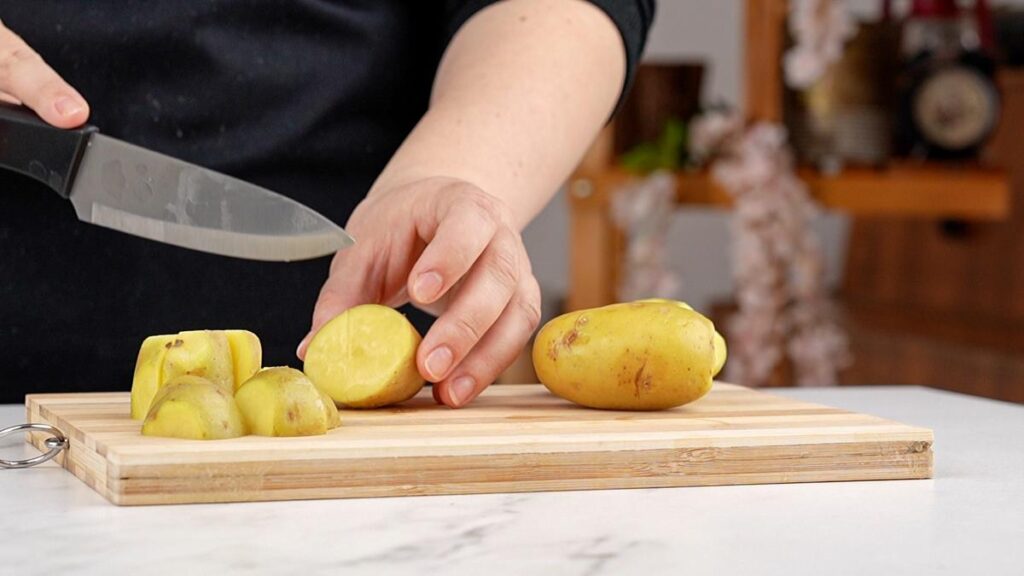 potatoes being sliced on cutting board