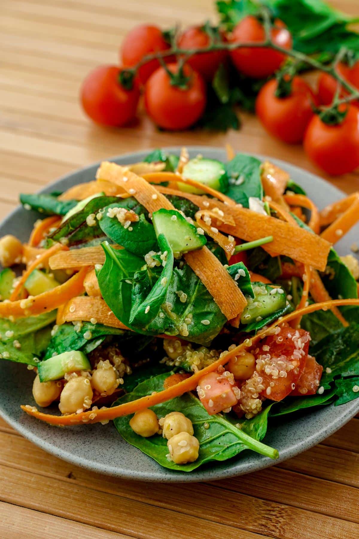 blue gray plate of rainbow salad on wood table by cherry tomatoes