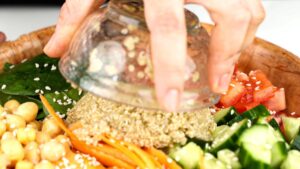quinoa being put into bowl of salad