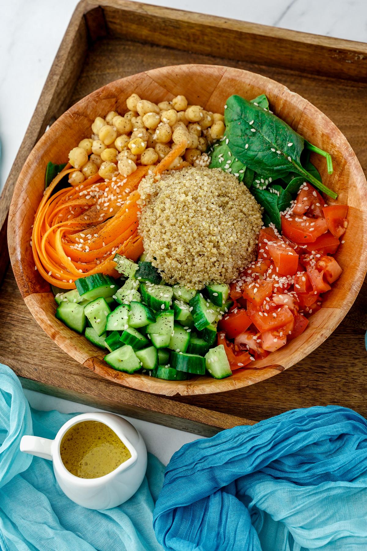 wooden bowl of rainbow salad sitting on wood tray by teal napkin
