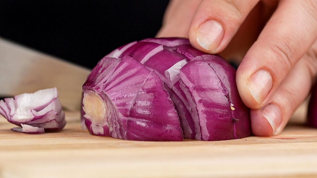 chopping red onion on wood cutting board