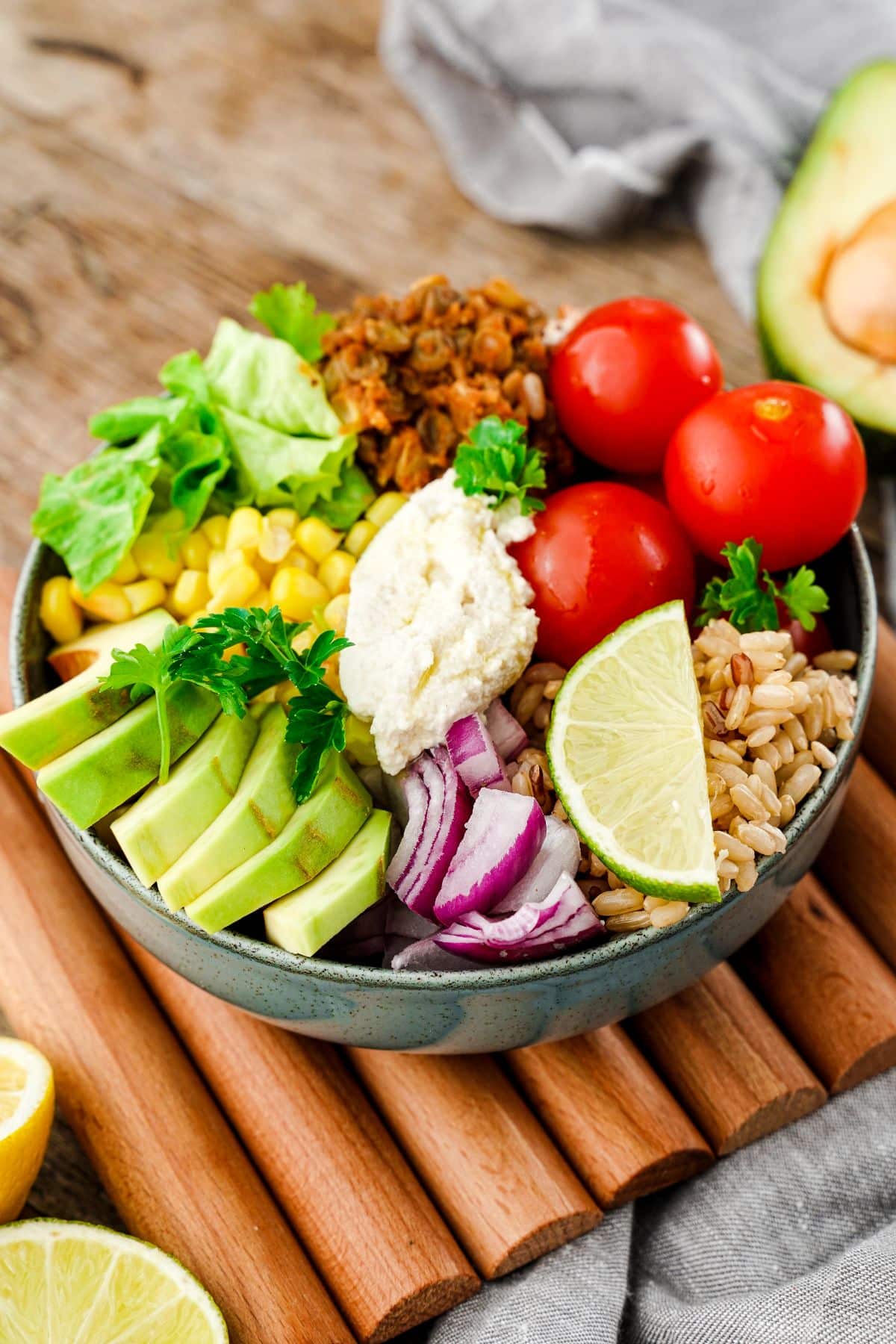 blue bowl of taco salad topped by fresh vegetables and cashew sour cream