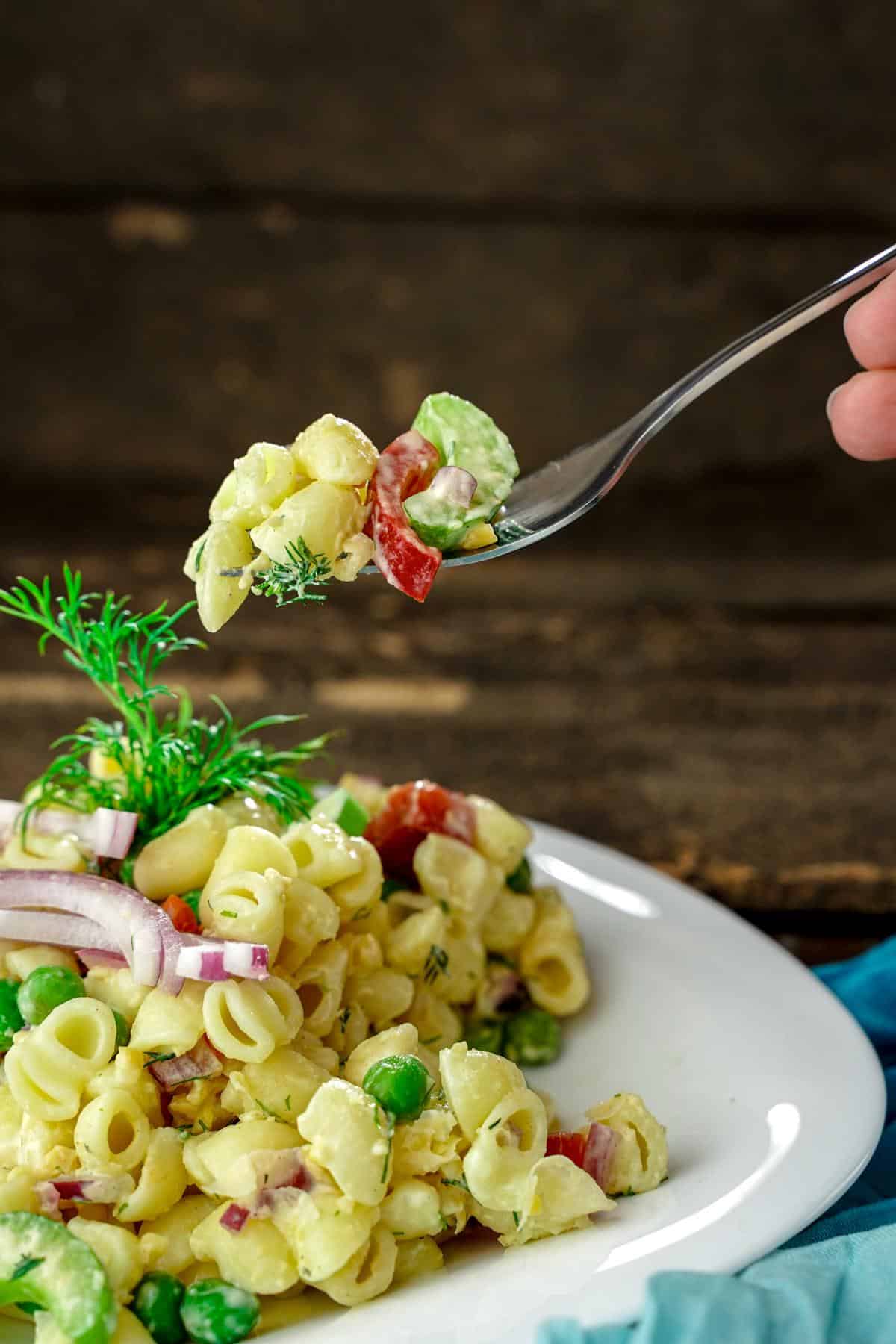 fork of tuna pasta salad held above white bowl