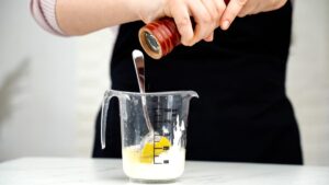 pepper being added to glass measuring cup of mayo