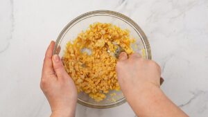 chickpeas in glass bowl being mashed with fork