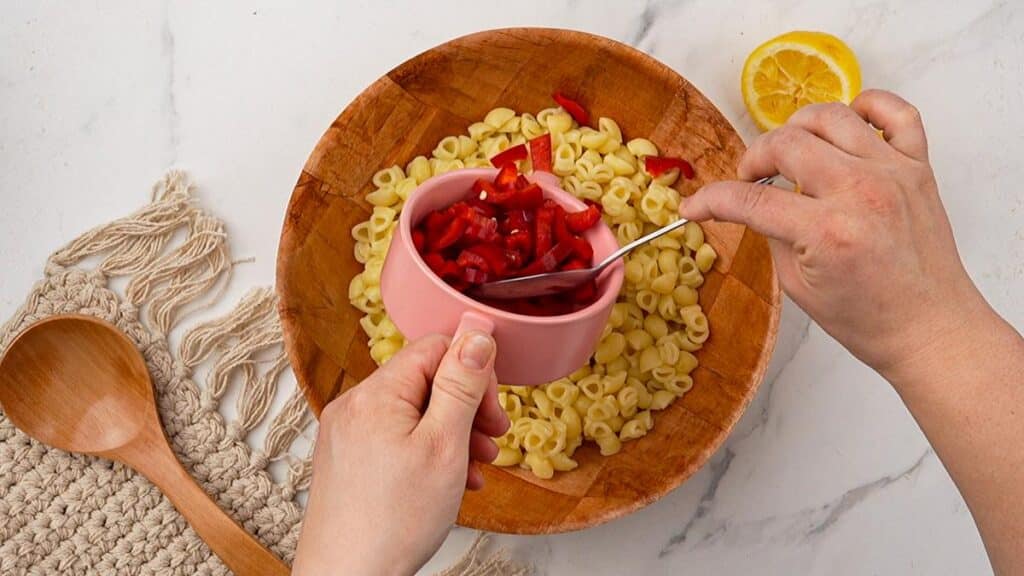 peppers being added to bowl of pasta