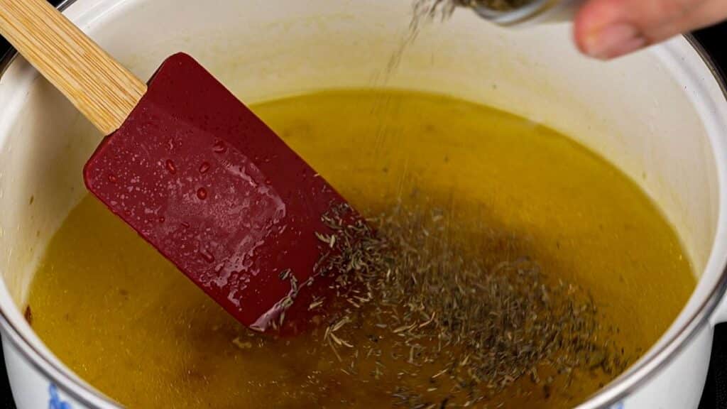 broth and herbs being stirred in saucepan