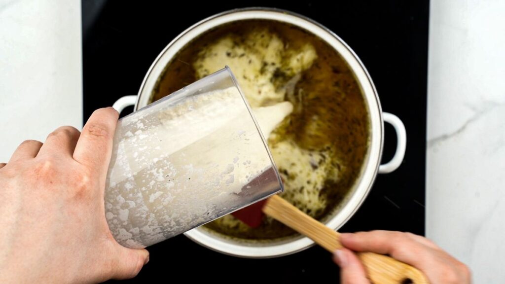 cashew cream being poured into saucepan for soup