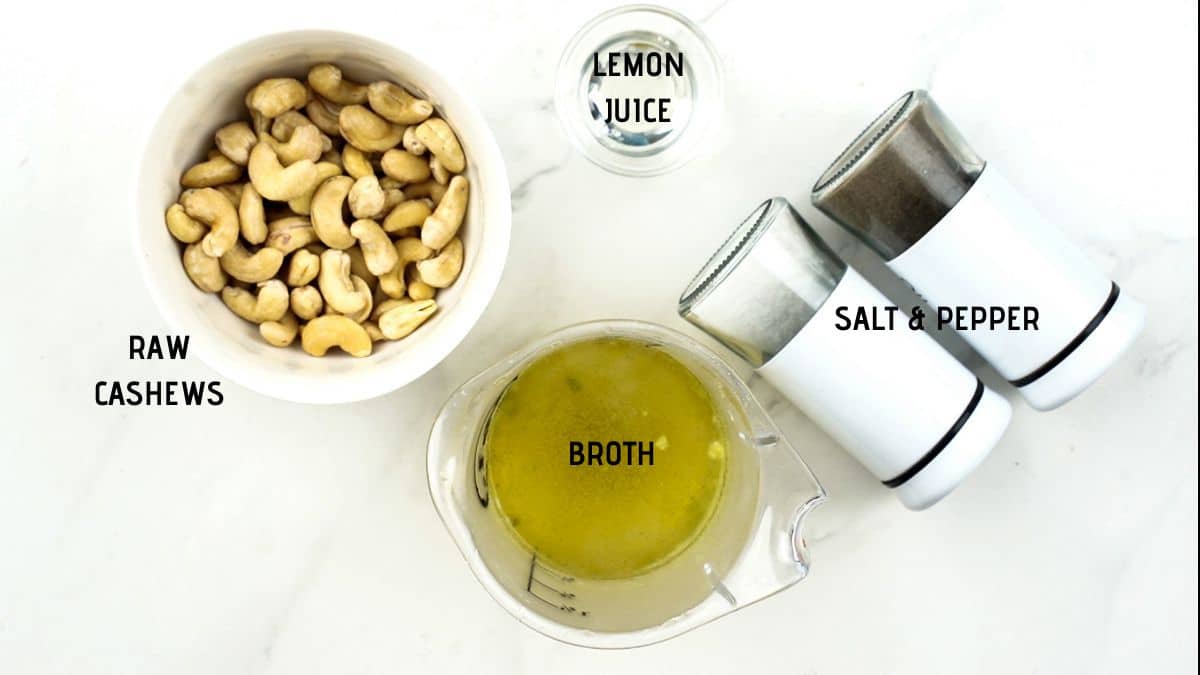 white bowl of cashews next to cup of broth and salt and pepper shakers