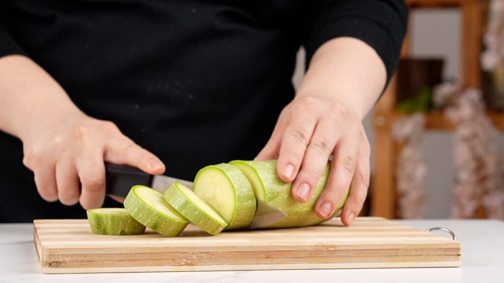 zucchini being chopped on cutting board