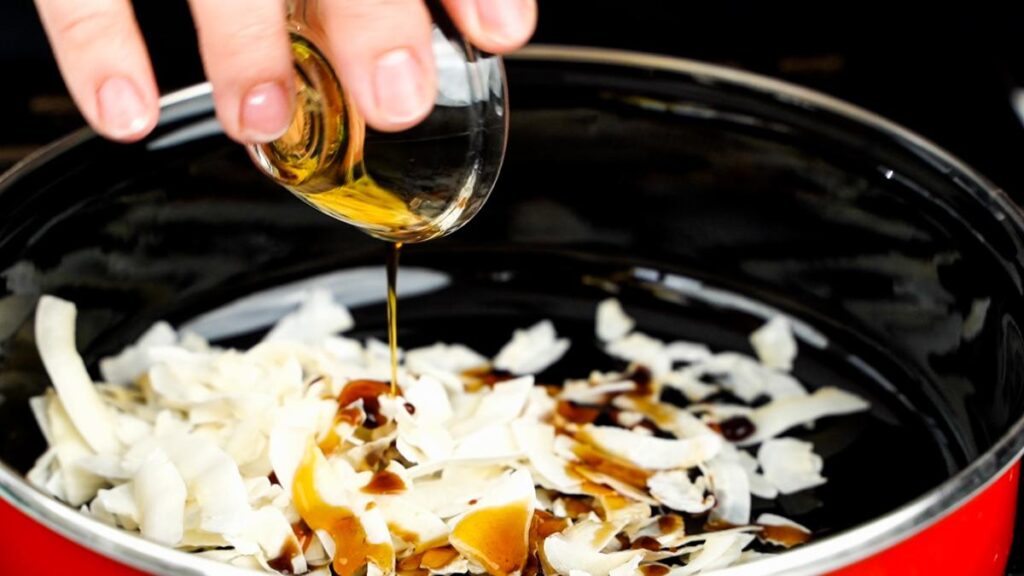 sauce being added to skillet of coconut flakes