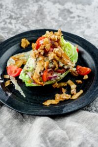 round black plate of wedge salad on top of gray napkin