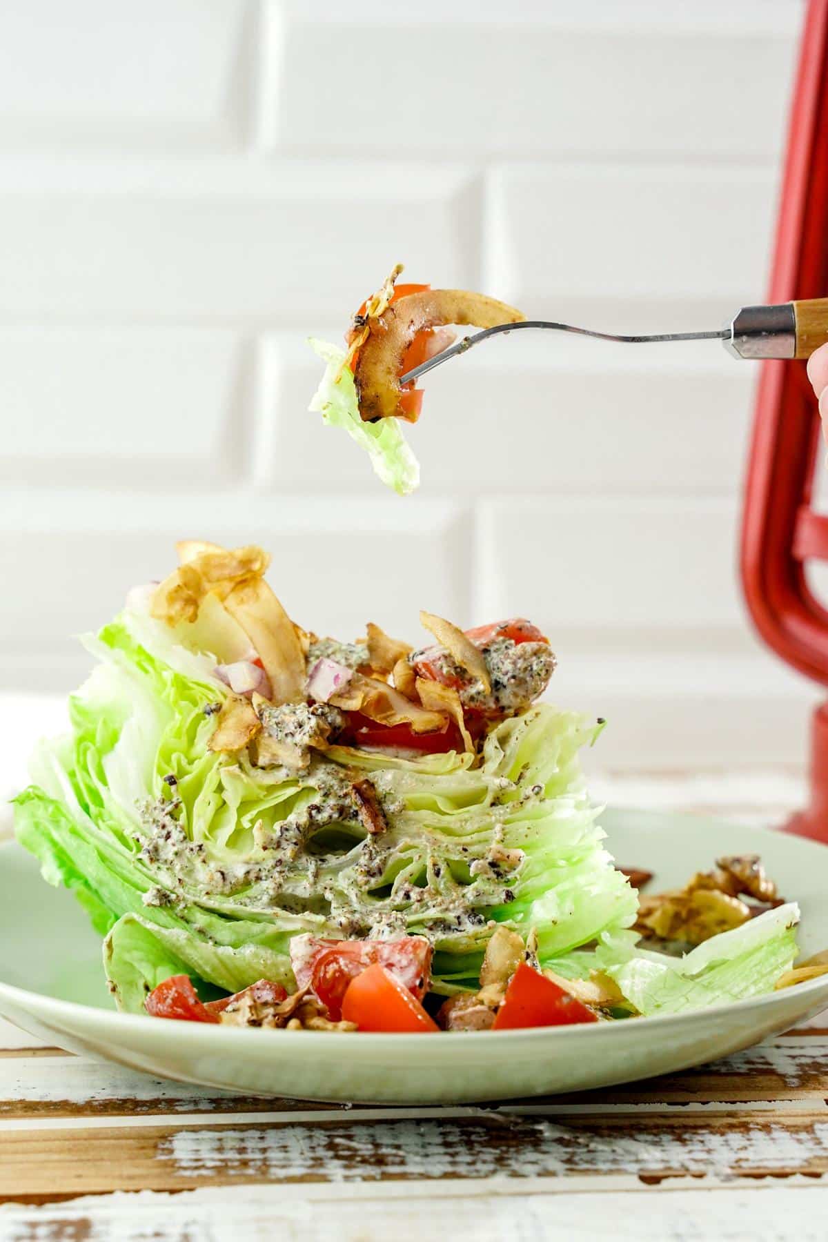 fork of salad held above wedge on white plate