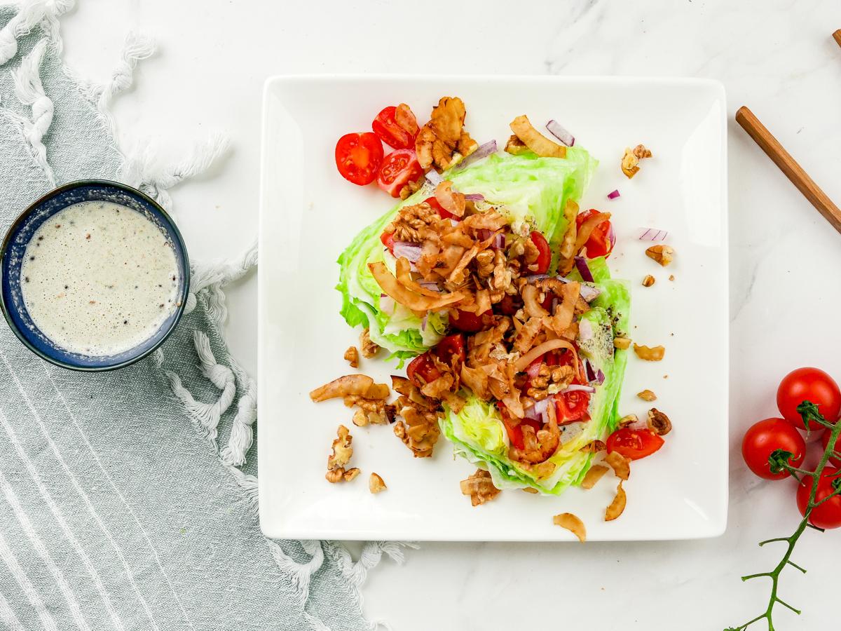 square white plate holding wedge salad on table by gray napkin