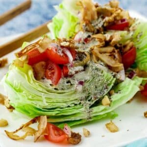 wedge salad with tomatoes, coconut bacon, and hemp dressing on white plate