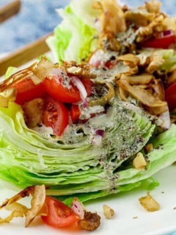 wedge salad with tomatoes, coconut bacon, and hemp dressing on white plate