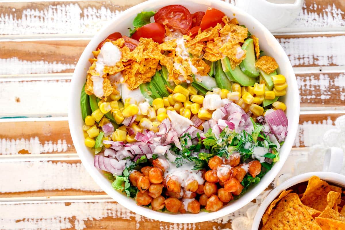 round white bowl of bright veggie salad on rustic wood table 