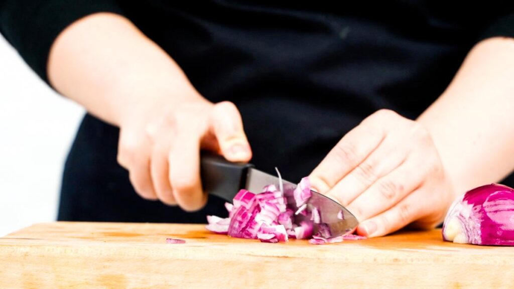 red onion being chopped on cutting board