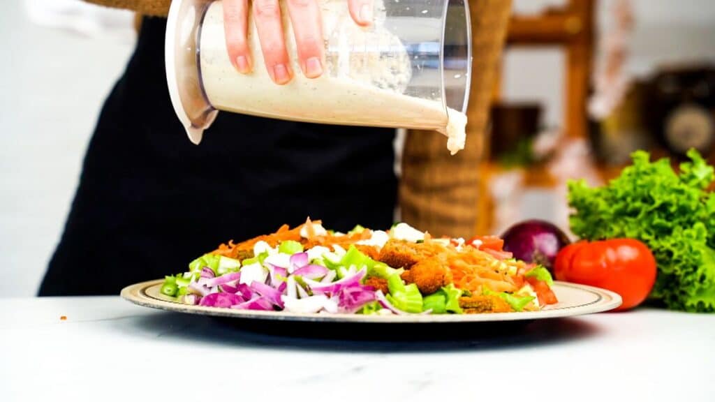 dressing being poured over plate of salad
