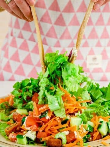 wooden forks tossing salad in bowl