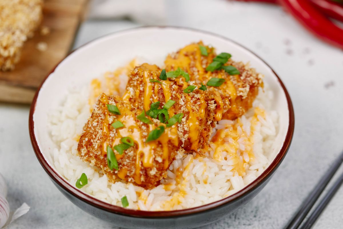 bowl of rice and breaded tofu on marble table by red napkin