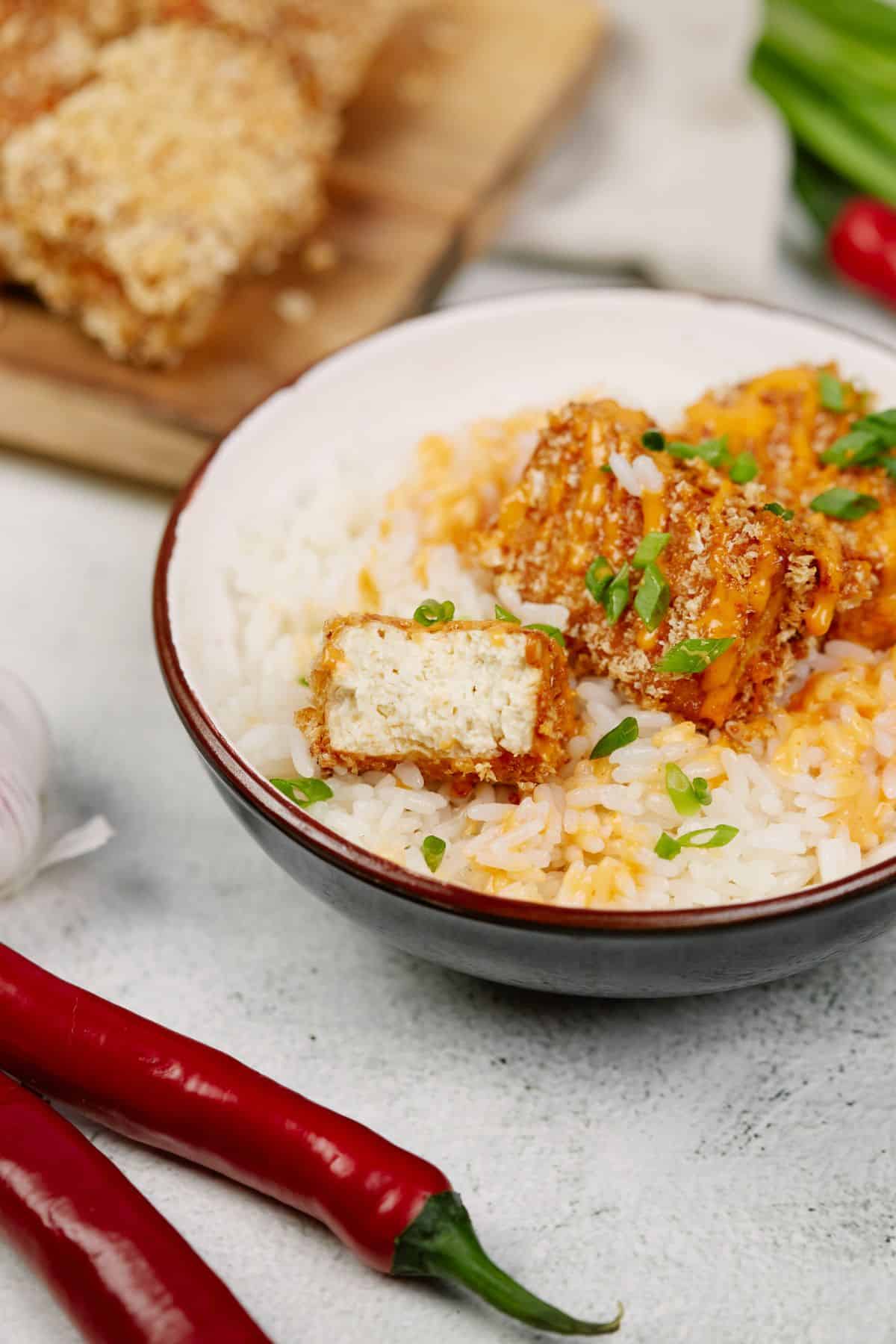 tofu and rice with sauce and herbs on top