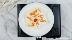 white skillet on hotplate cooking a vegan crunchwrap supreme