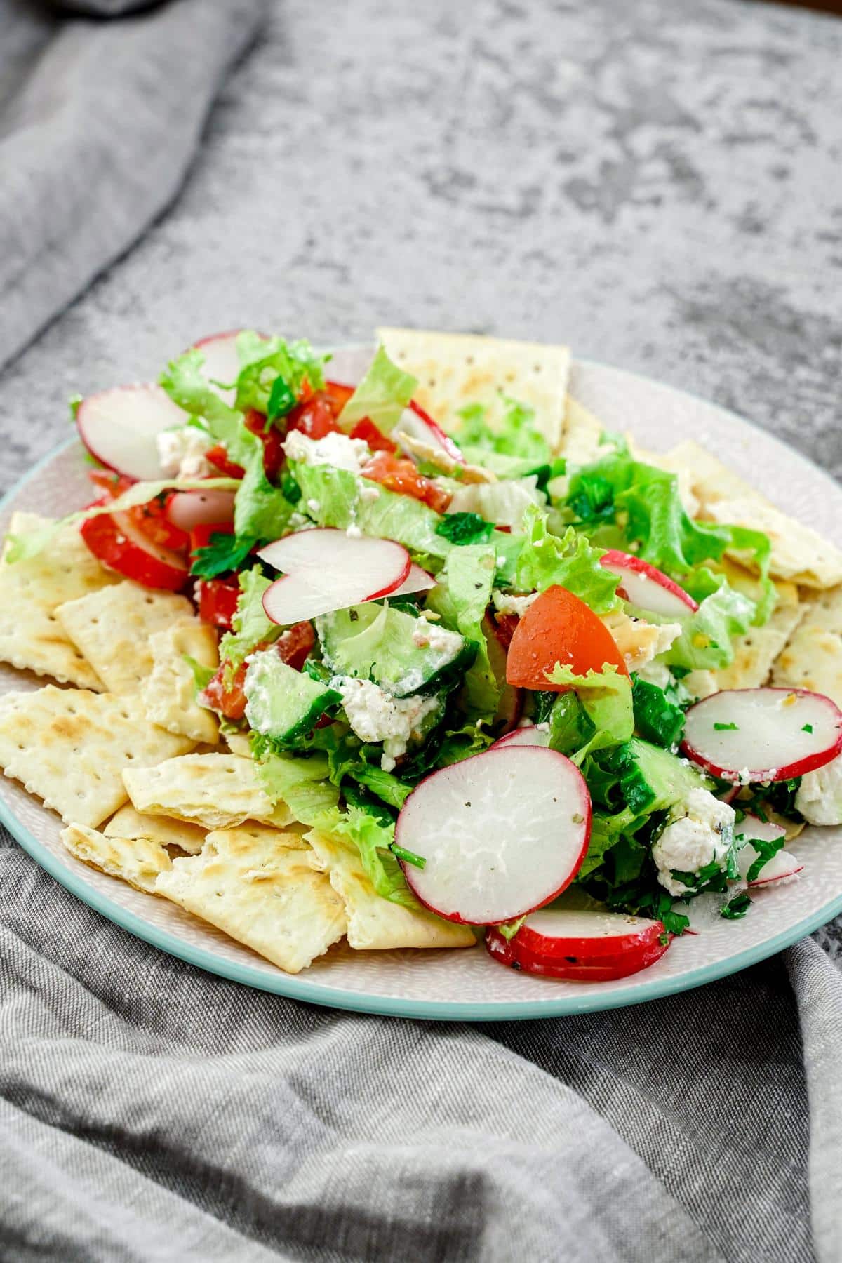 white plate of fattoush salad  on top of gray napkin