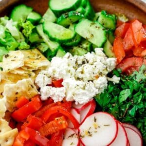 wood bowl of salad with vegan feta on top