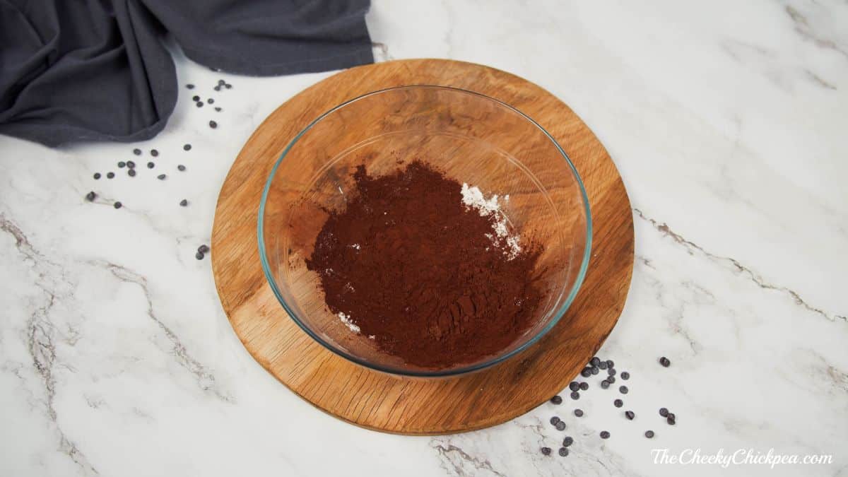 cocoa powder in glass bowl on round wooden slab