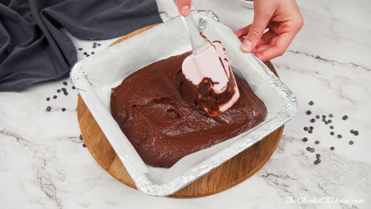 spatula spreading brownie batter into square pan