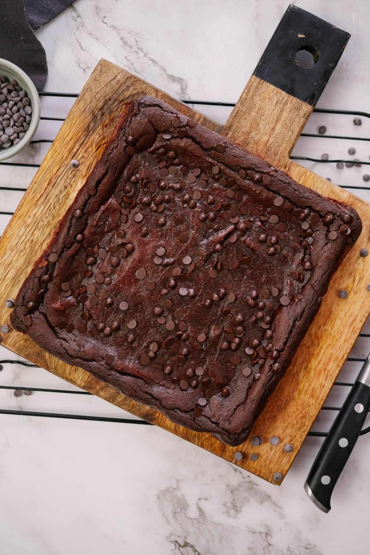 square of baked brownies on wooden cutting board on top of wire rack