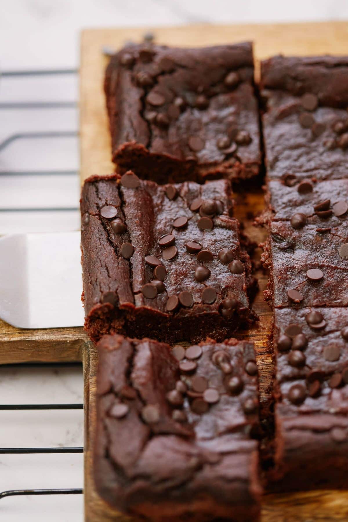 brownies sliced on wood cutting board with spatula holding one out