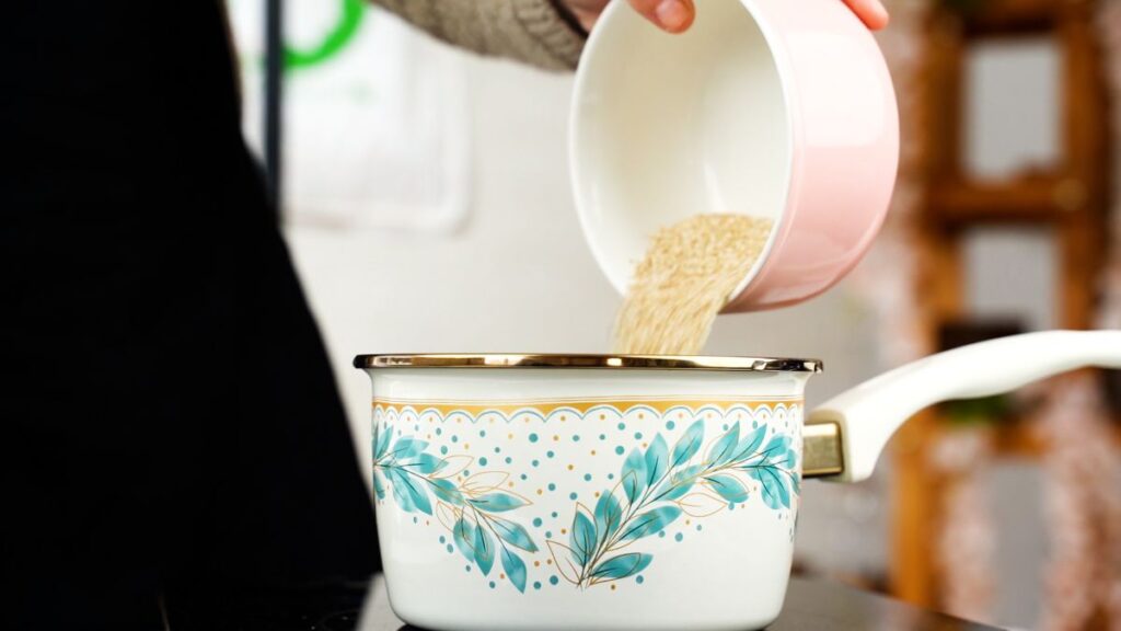 quinoa being poured into white and blue floral saucepan