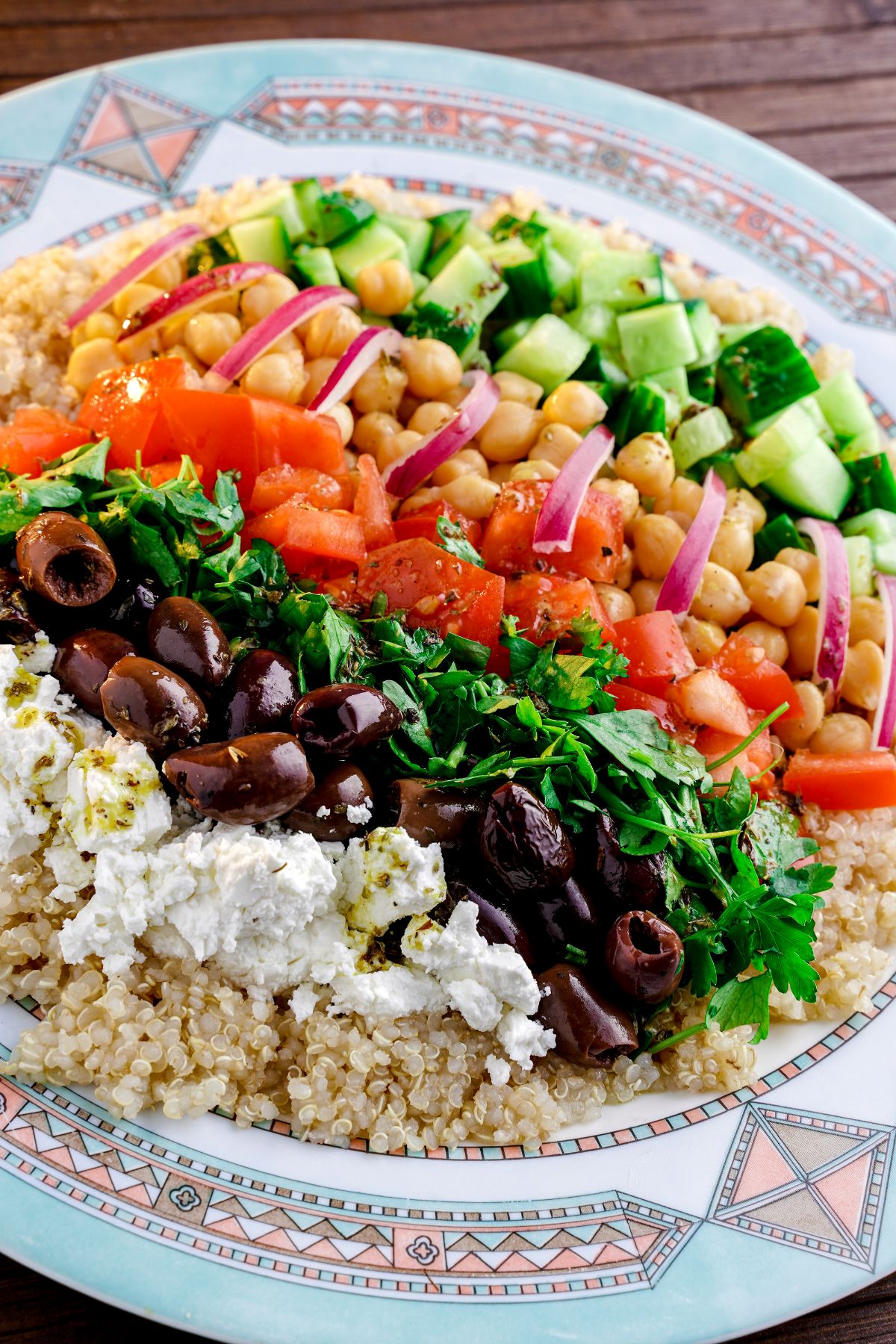 blue patterned plate topped with layers of vegetables and quinoa for salad